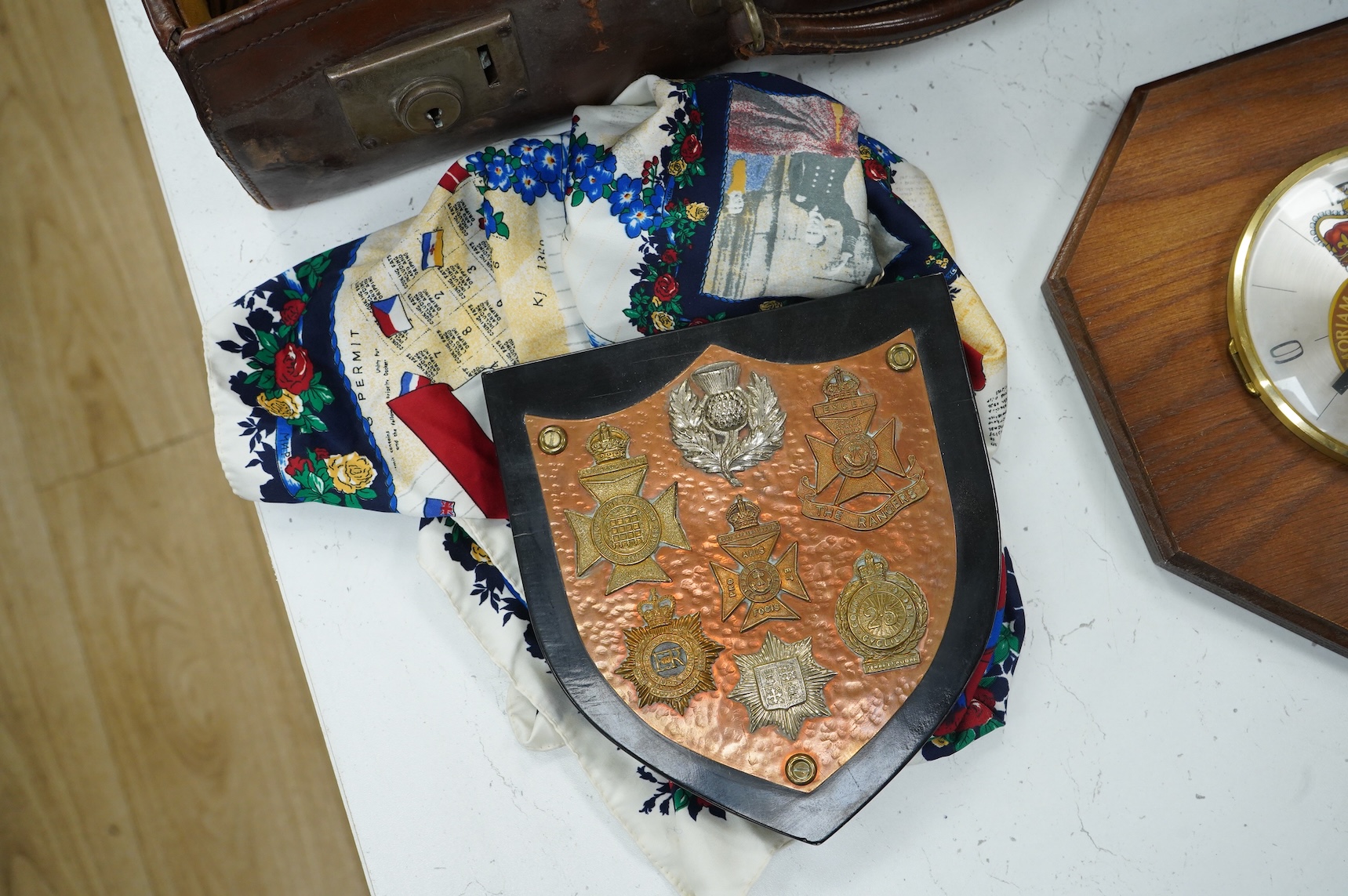 A suitcase of military related items, including; a Manchester Guardian issued early 20th century map of Europe printed on cotton, a First World War trench art match holder the base formed from a cartridge case, two swagg